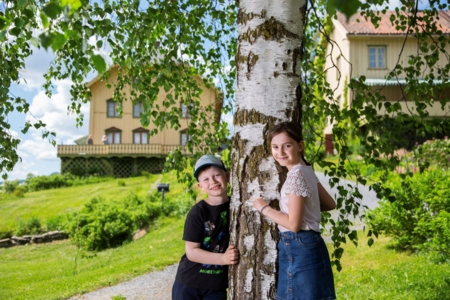 Barn som lener seg mot et tre